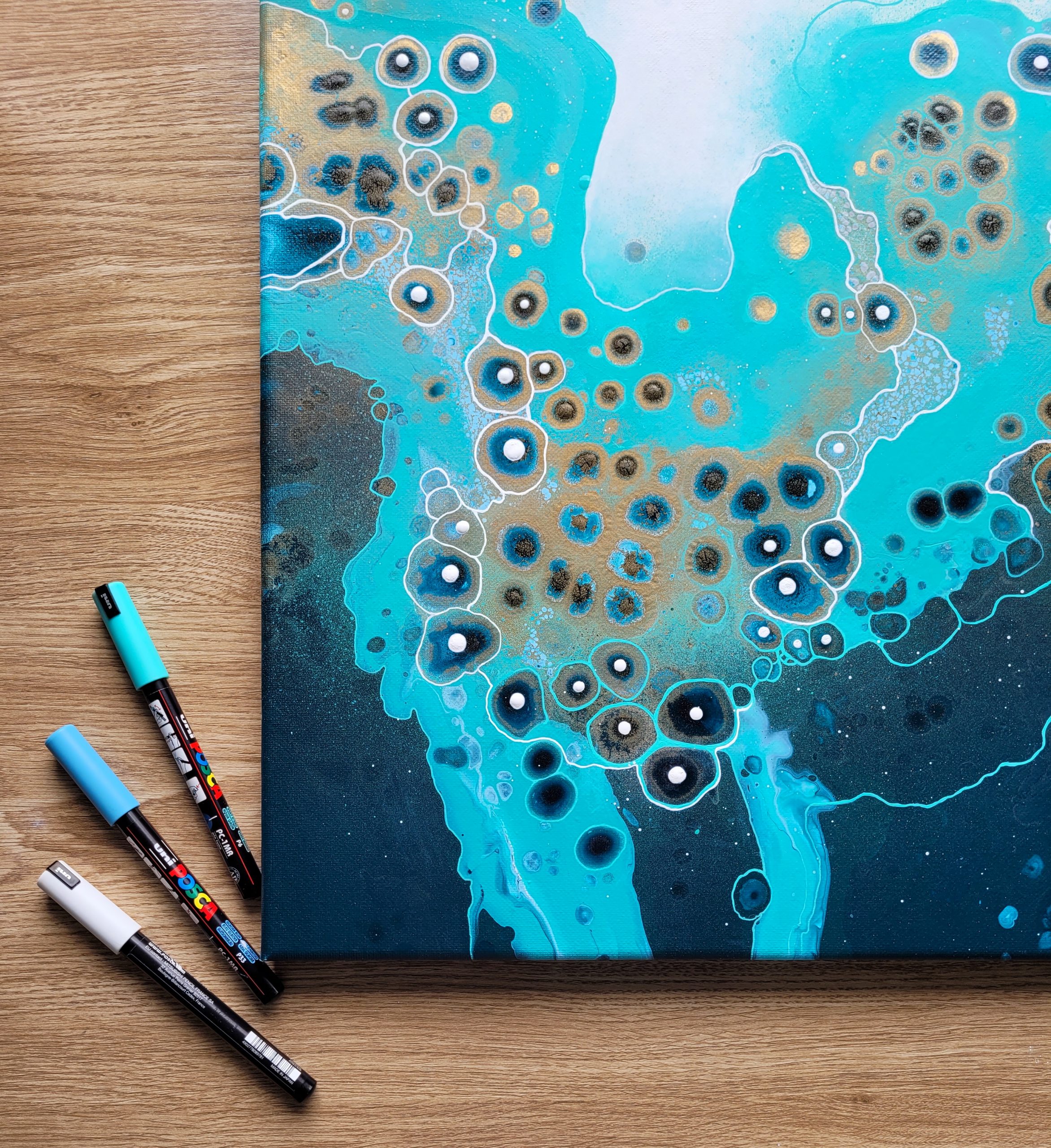 Close-up of turquoise abstract acrylic painting with organic circular patterns and fluid textures.